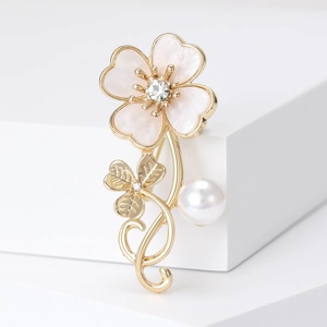 Detailed close-up of a gold floral brooch with pink shell petals and a pearl drop