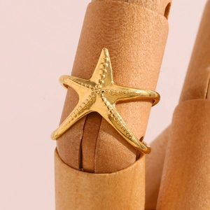 Détail d'une bague étoile de mer dorée 18 carats sur main avec finition polie