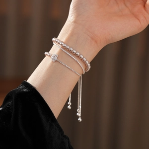 Gros plan de bracelets fleurs en zircon et perles avec fermoir réglable sur un poignet