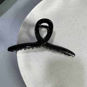 Top view of 13cm glossy black large hair claw clip with interlocking teeth on a grey surface