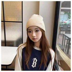Detail view of beige ribbed knit beanie featuring mountain embroidery on the side
