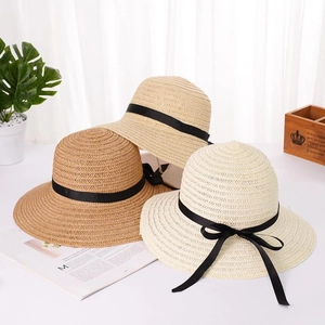 Dettaglio di cappelli estivi in paglia in varie tonalità con eleganti fiocchi neri