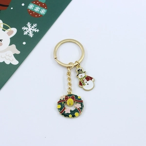 Close-up of a Christmas enamel keychain with Santa and snowflake charms on golden chain