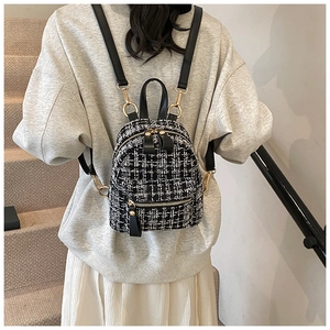 Detail of tweed checkered mini backpack worn by model on stairs with leather straps
