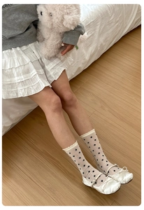 Detailed view of white polka dot socks with ruffled edges and ballet flat shoes