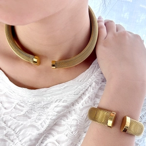 Macro shot of gold mesh choker and cuff bracelet set showing woven texture details
