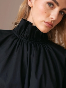 Detail of the high ruffled collar and pleated neckline texture on this black shirt