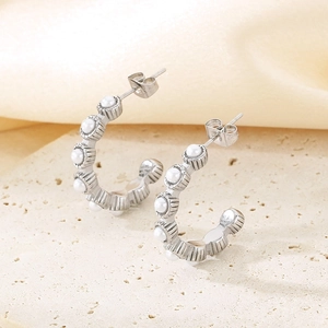 Vue détaillée des boucles d'oreilles argentées en C avec perles sur pierre et satin