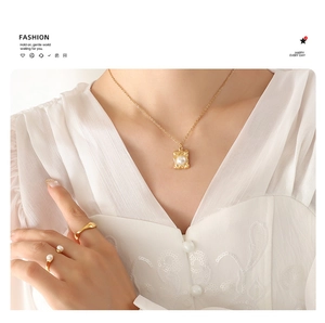 Close-up of a French style gold pendant necklace and imitation pearl ring on a model