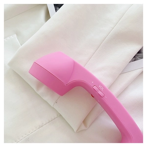 Detailed close-up of pink patent leather crossbody bag with vintage handset design