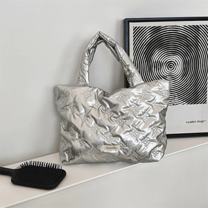 Close-up of silver quilted tote bag with 3D bow patterns and integrated handles