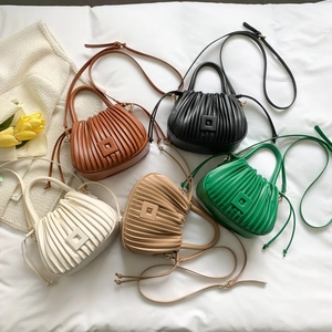 Detailed view of pleated bucket bags in caramel, black, cream, beige, and green colors