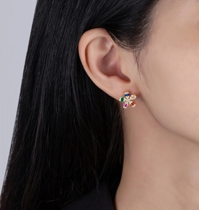 Macro close-up of a flower stud earring with five colorful square-cut zircons on a model