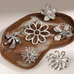 Minimalist silver stainless steel floral brooches with pearl accents in ceramic tray