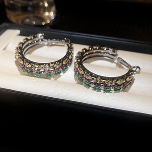 Macro view of multi-row colorful zircon hoop earrings displayed in a beige jewelry box