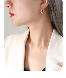 Detail of twisted 18K gold plated hoop earrings with zircon stones on model