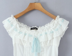 Close-up of white French style top featuring blue lace ribbon and ruffled eyelet details