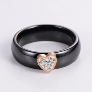 Detail view of a black ceramic ring with a gold heart pendant and micro-set diamonds