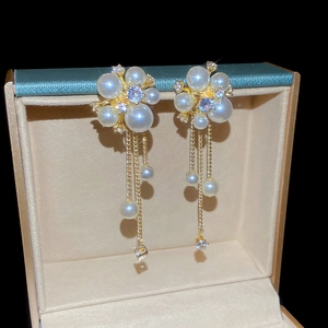 Detail view of flower-shaped pearl tassel earrings with zircon in a premium gold finish