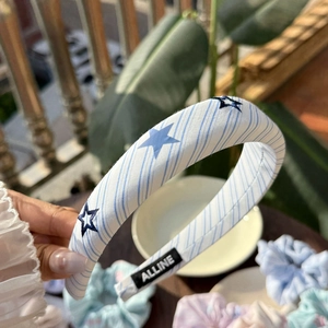 Close-up of padded blue striped headband with star patterns and woven brand label