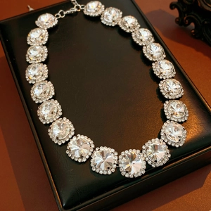 Close-up of silver-tone necklace with large round rhinestones on black leather stand