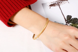 Close-up of minimalist gold matte titanium steel bangle with fine frosted texture on wrist