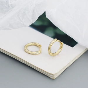 Macro view of gold-plated silver huggie hoop earrings with sparkling zircon stones