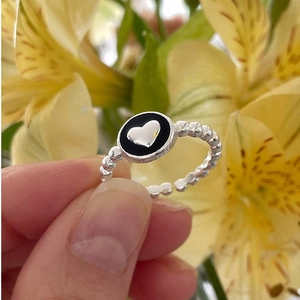 Macro shot of a beaded silver ring featuring a black enamel circle and a tiny silver heart
