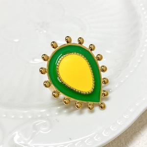 Detail of teardrop avocado flower ring with enamel finish on white embossed plate