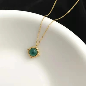 Collier vintage en or avec pendentif en agate verte suspendu sur un bol en céramique