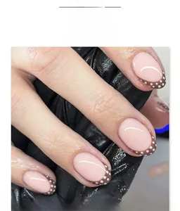Macro shot of brown French tip press-on nails with white polka dots on natural oval shape