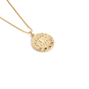 Detail of gold evil eye necklace featuring hammered texture and colorful zircon stones