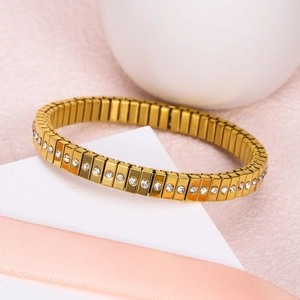 Close-up of golden elastic bracelet with rectangular links and inlaid sparkling crystals