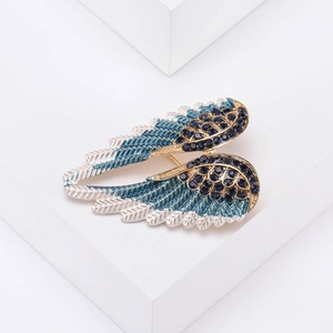 Detail of angel wing brooch with blue gradient enamel and crystals on white blocks