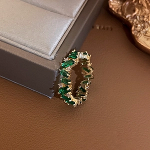 Macro shot of gold-plated eternity ring featuring emerald-cut crystals and white diamonds