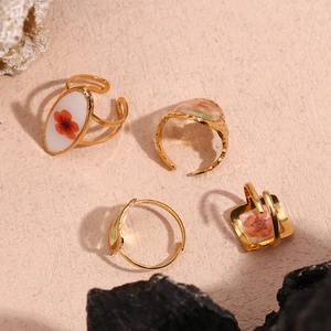 Detail of 18K gold-plated rings with hammered textures and oval floral patterns on stone