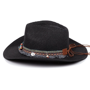 Detail of black straw hat featuring colorful Bohemian woven ribbon and ethnic pendants
