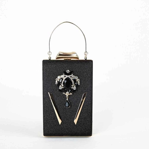 Detail van zwarte avondclutch met gouden handvat versierd met strass en edelstenen