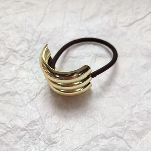 Macro shot of gold layered curved metal cuff hair tie with high elastic black rope