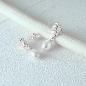 Macro shot of S925 silver twist star hoop and teardrop pearl on a white branch
