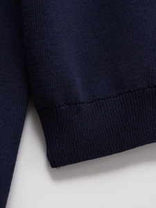 Detailed close-up of the ribbed cuff and tight knit texture on a navy blue knit sweater