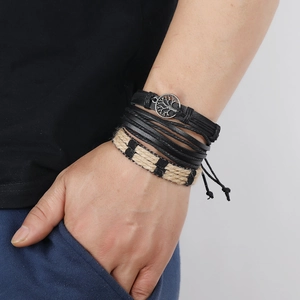 Close-up of layered leather bracelets featuring life tree pendant and braided hemp ropes