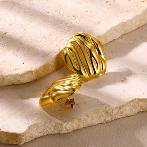 Detailed close-up of golden irregular textured earrings on natural stone surface