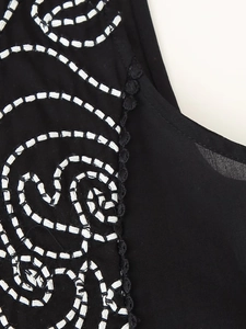 Detailed view of white swirl embroidery on black sleeveless shirt with lace scalloped edges