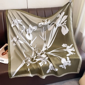 Macro detail of olive green silk scarf featuring delicate white iris floral patterns