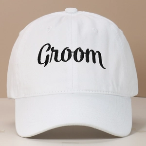 Close-up of white washed cotton baseball cap featuring black Groom cursive embroidery