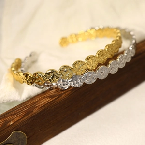 Minimalist hammered texture open bangle in gold and silver finish on a wooden stand