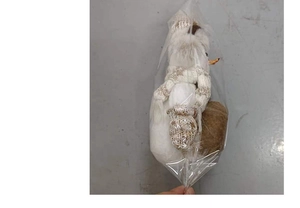 Détail d'un bonhomme de neige en peluche avec bonnet tricoté beige sous emballage sac