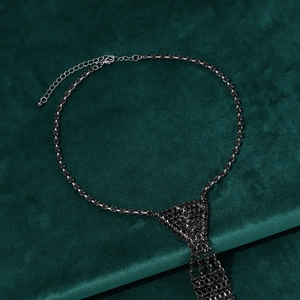 Macro shot of long black rhinestone tie necklace with tassels on green velvet