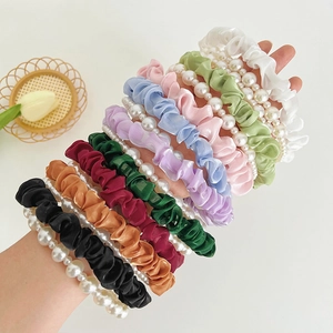 Macro view of multi-color ruffled fabric scrunchies with elegant pearl bead embellishments